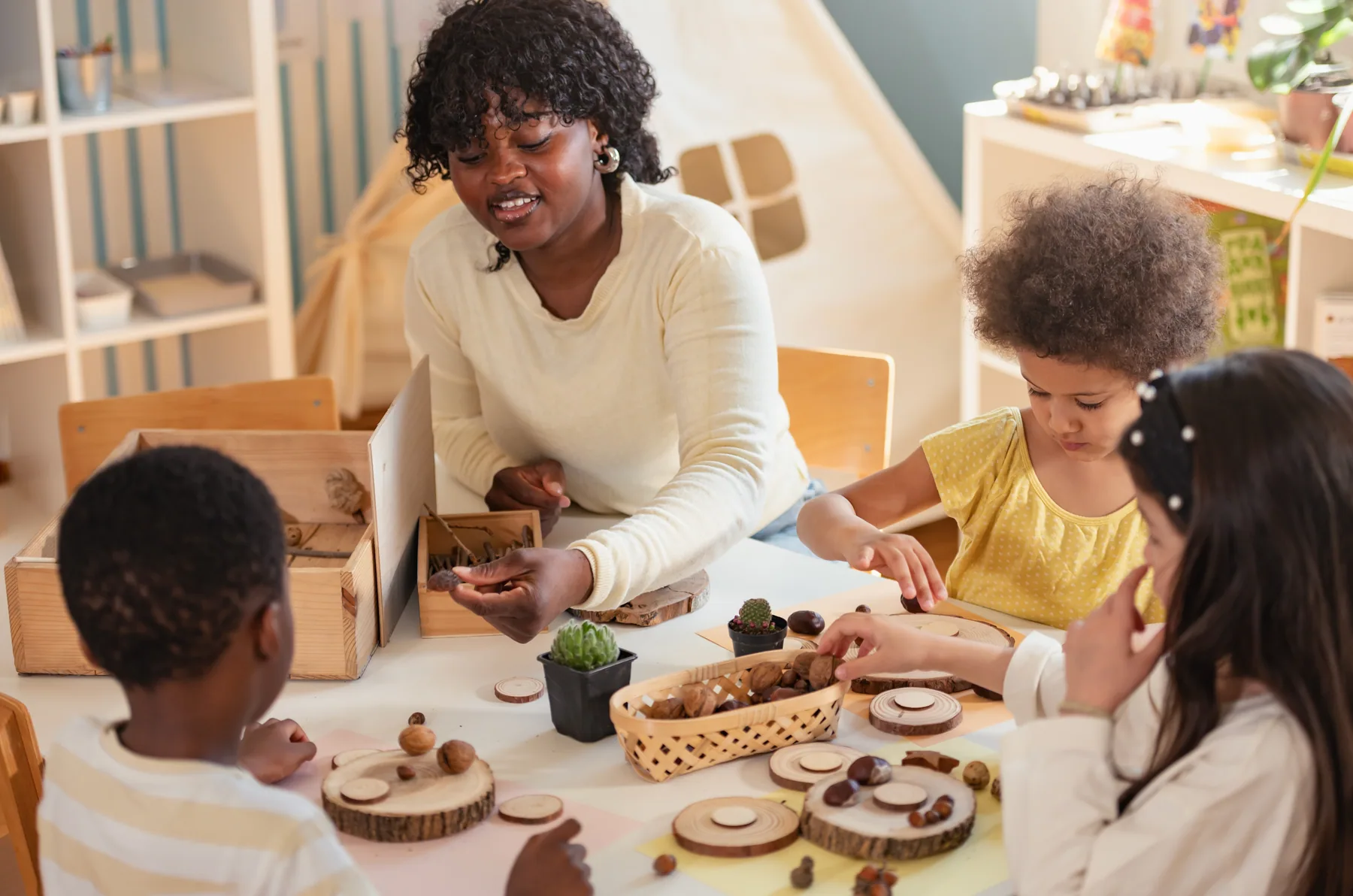 Eine pädagogische Fachkraft und Kinder erkunden gemeinsam Naturmaterialien.